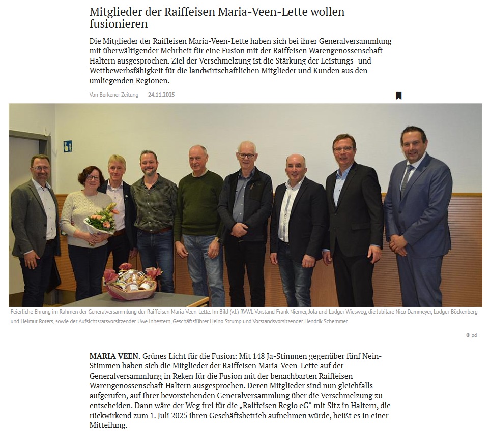 Acht Personen stehen freundlich lächelnd in einem Raum mit weißer Wand und Holzboden